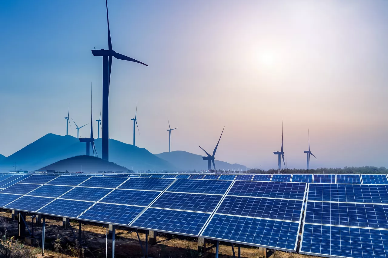 Sustainable energy concept; rows of solar panels with windmills in background