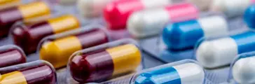 Selective focus on blue-white capsule pills in blister pack. Pharmaceutical industry. Drug package. Pharmaceutics concept. Drug use in hospital or drugstore product. Health budget. Global healthcare.