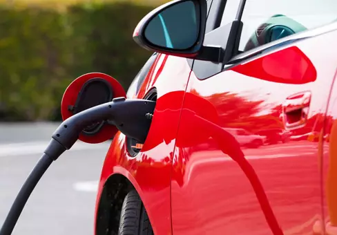 An electric vehichle, car charging at a public station
