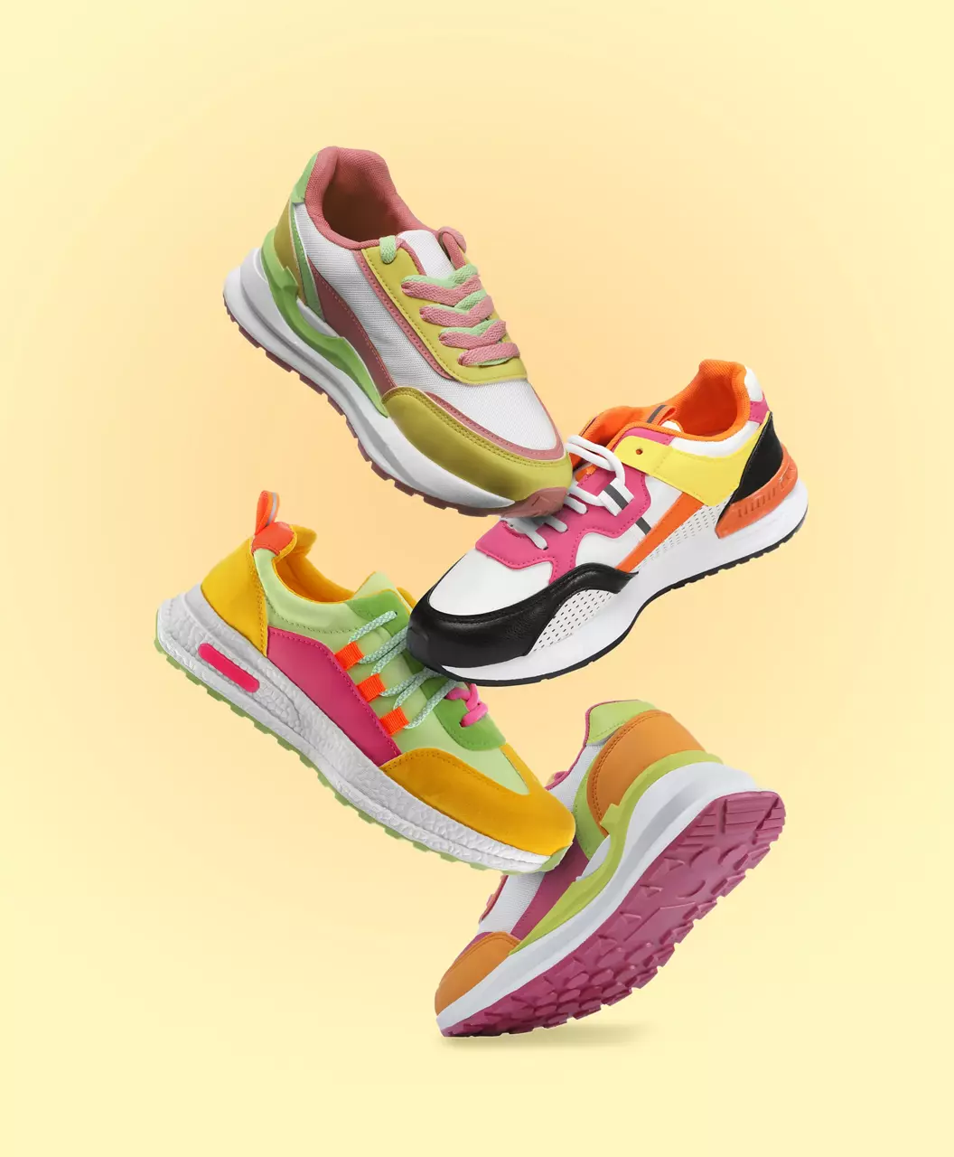 Different sneakers falling on beige gradient background